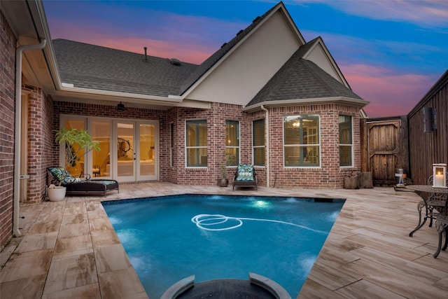 pool at dusk with a patio and french doors