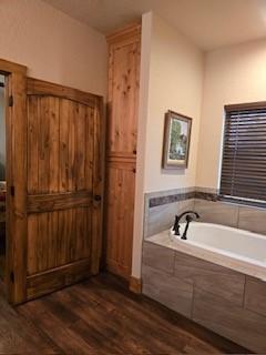 bathroom featuring hardwood / wood-style floors and tiled tub