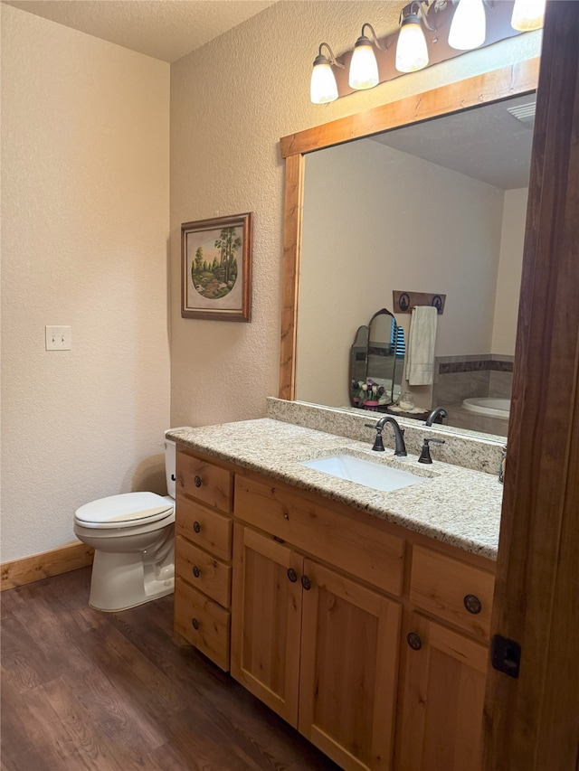 bathroom with wood-type flooring, toilet, and vanity