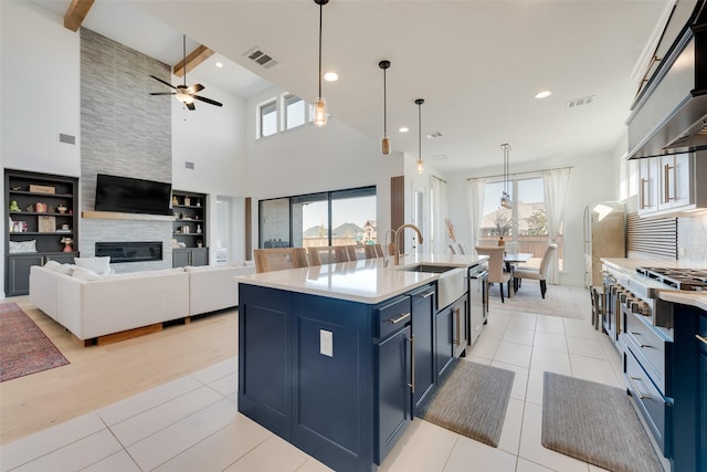 kitchen with exhaust hood, a sink, stainless steel appliances, visible vents, and blue cabinets