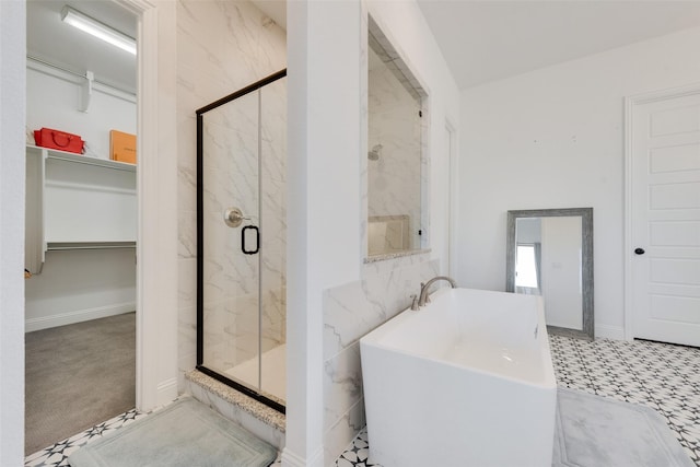 bathroom featuring a walk in closet, a freestanding bath, and a marble finish shower
