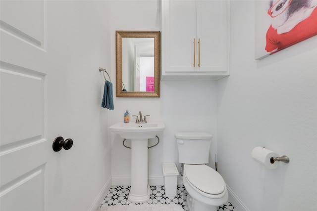 half bathroom with baseboards and toilet