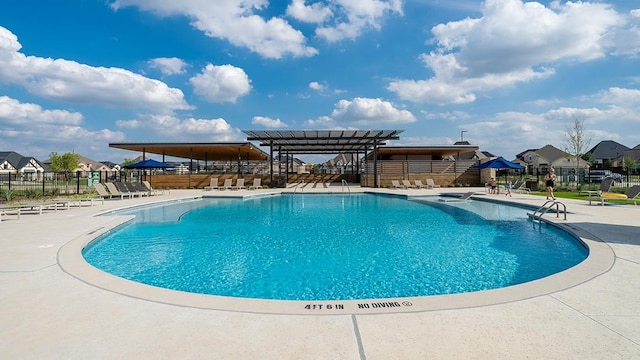 community pool featuring fence, a residential view, and a patio area