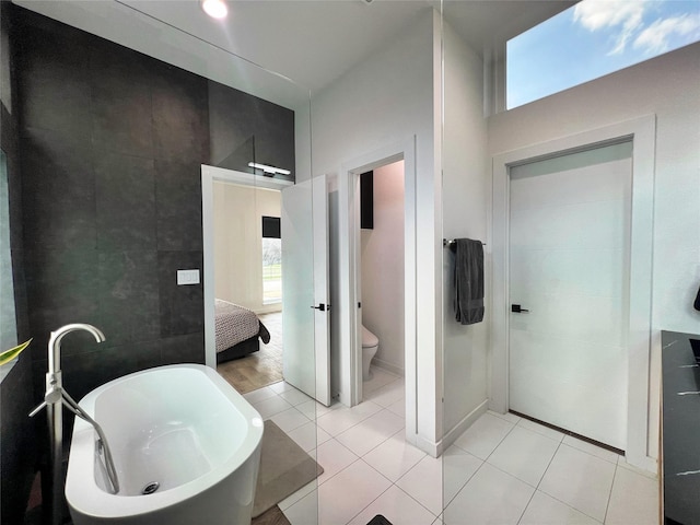 full bathroom with a high ceiling, a freestanding bath, tile patterned flooring, ensuite bath, and toilet
