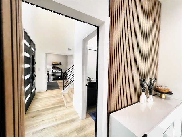 hall featuring stairs, light wood-style flooring, and visible vents