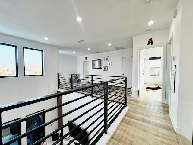 corridor featuring visible vents, recessed lighting, a wealth of natural light, and an upstairs landing