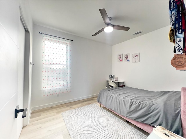 bedroom with ceiling fan, visible vents, and wood finished floors