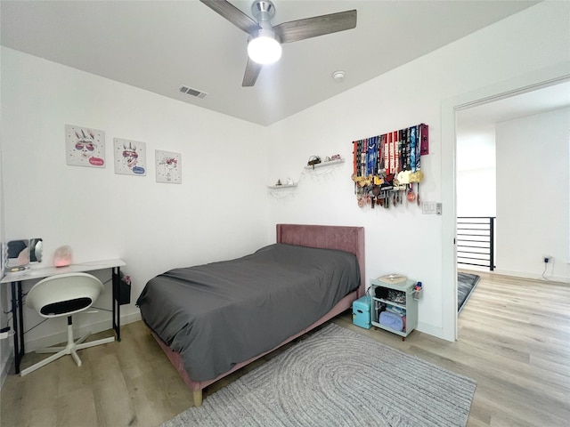 bedroom featuring ceiling fan, baseboards, visible vents, and wood finished floors