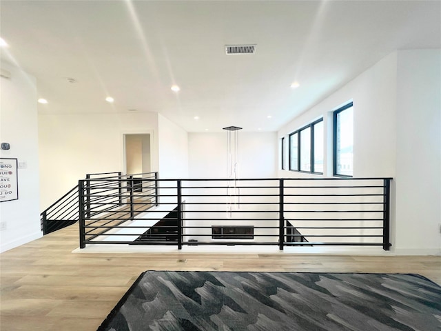 interior space with recessed lighting, baseboards, an upstairs landing, wood finished floors, and visible vents