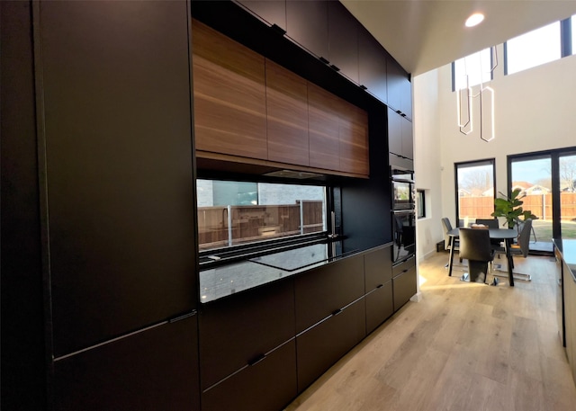 kitchen with visible vents, a towering ceiling, open floor plan, modern cabinets, and a sink