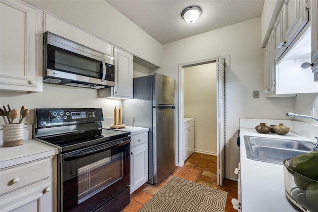 kitchen featuring appliances with stainless steel finishes, sink, a textured ceiling, and white cabinets