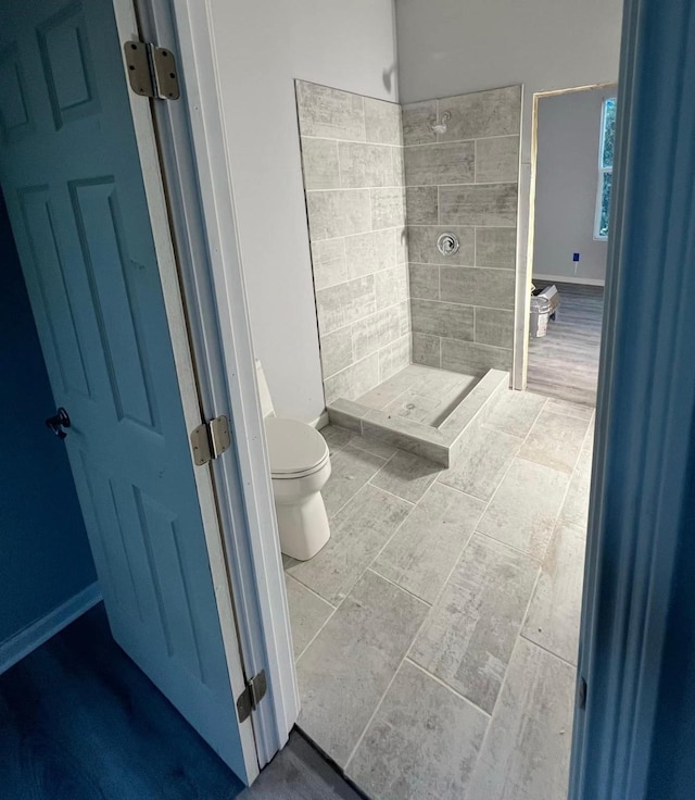full bath featuring a stall shower, toilet, and baseboards
