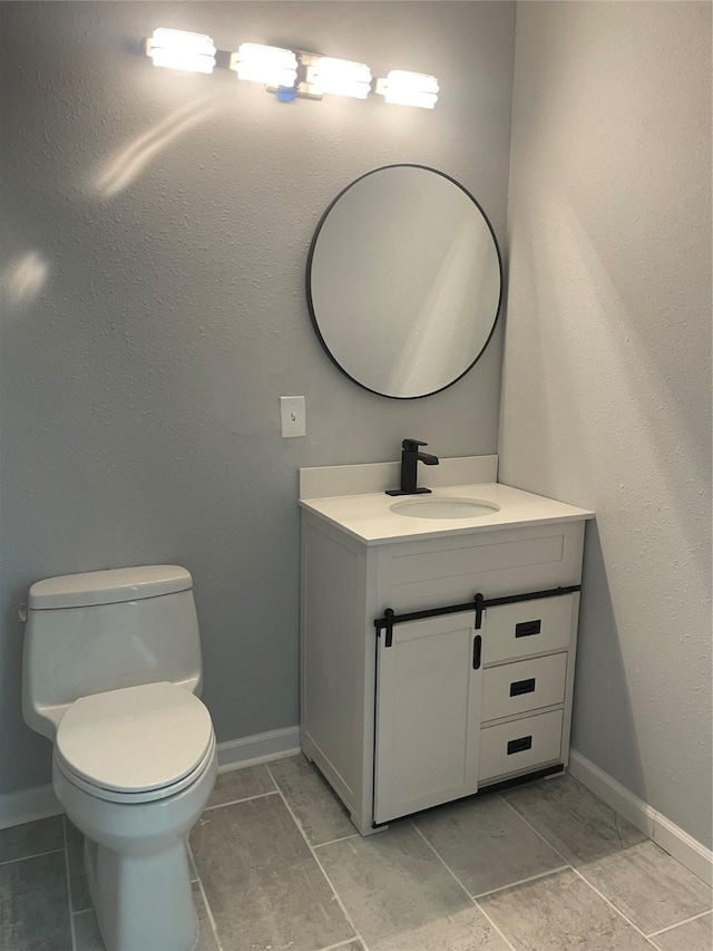 bathroom featuring toilet, vanity, and baseboards