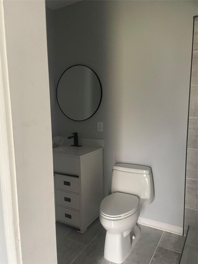 bathroom with vanity, toilet, baseboards, and tile patterned flooring