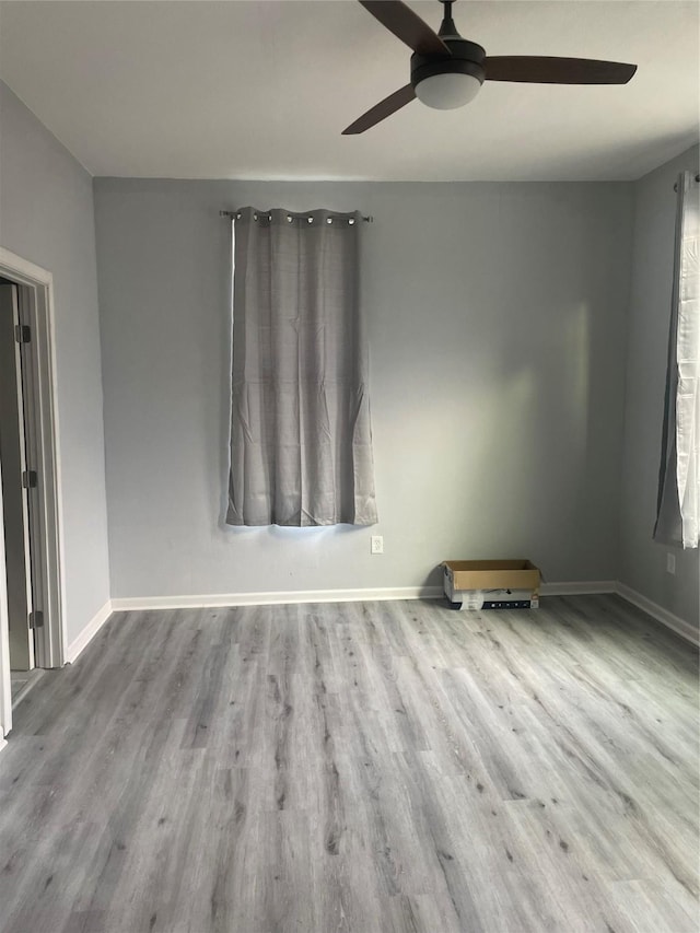spare room featuring wood finished floors, a ceiling fan, and baseboards