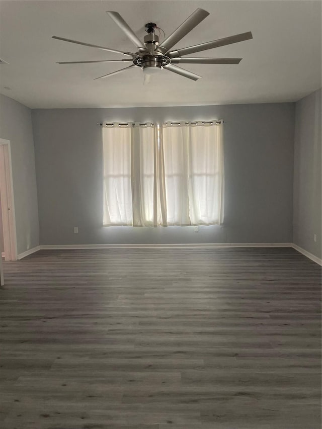 empty room featuring ceiling fan, baseboards, and wood finished floors