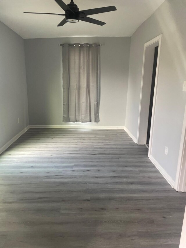 spare room featuring baseboards, ceiling fan, and wood finished floors