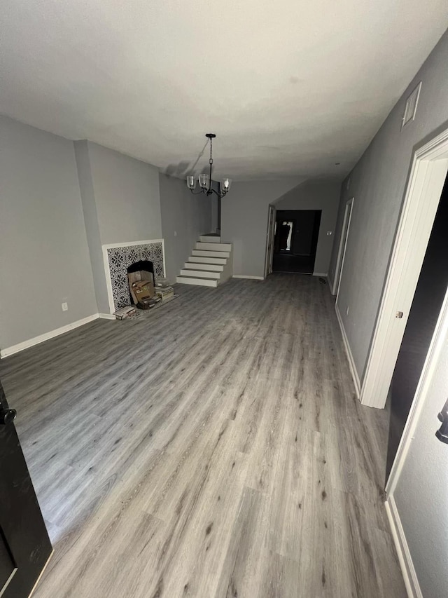 unfurnished living room featuring a notable chandelier, a fireplace, and light hardwood / wood-style flooring