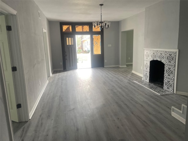 unfurnished living room with baseboards, an inviting chandelier, wood finished floors, and a tile fireplace