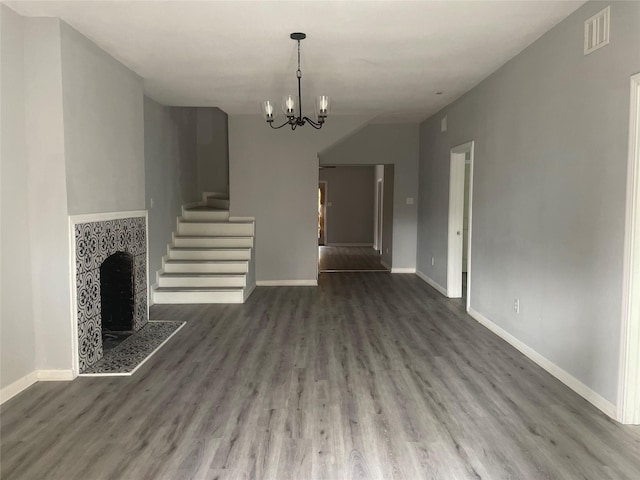 unfurnished living room featuring wood finished floors, visible vents, a chandelier, and baseboards