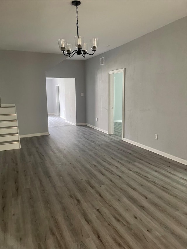 interior space with dark wood-type flooring, baseboards, visible vents, and a chandelier