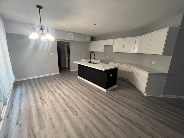 kitchen featuring visible vents, a notable chandelier, a sink, wood finished floors, and baseboards