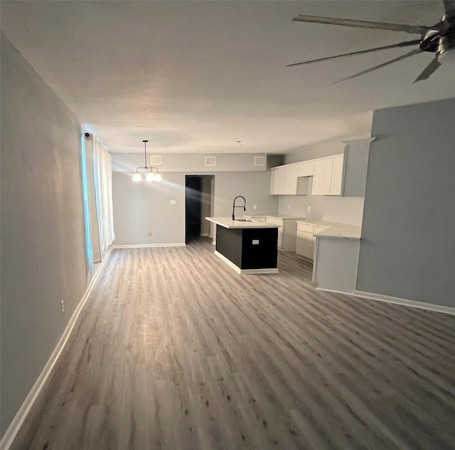 unfurnished living room with visible vents, baseboards, ceiling fan with notable chandelier, wood finished floors, and a sink