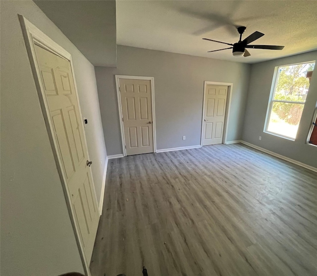 spare room with a ceiling fan, wood finished floors, baseboards, and a textured ceiling