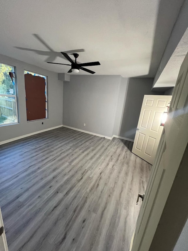 empty room with wood-type flooring, ceiling fan, and a textured ceiling