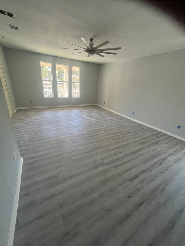 unfurnished room featuring visible vents, baseboards, a ceiling fan, and wood finished floors