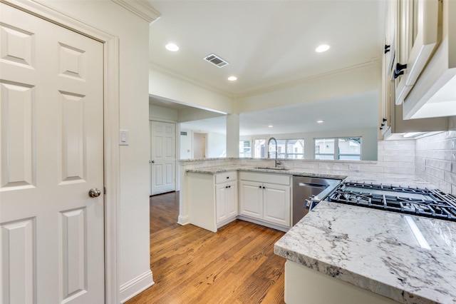 kitchen with sink, white cabinets, stainless steel dishwasher, light stone counters, and light hardwood / wood-style flooring