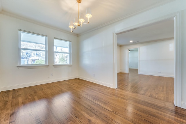 spare room featuring an inviting chandelier, ornamental molding, and hardwood / wood-style floors