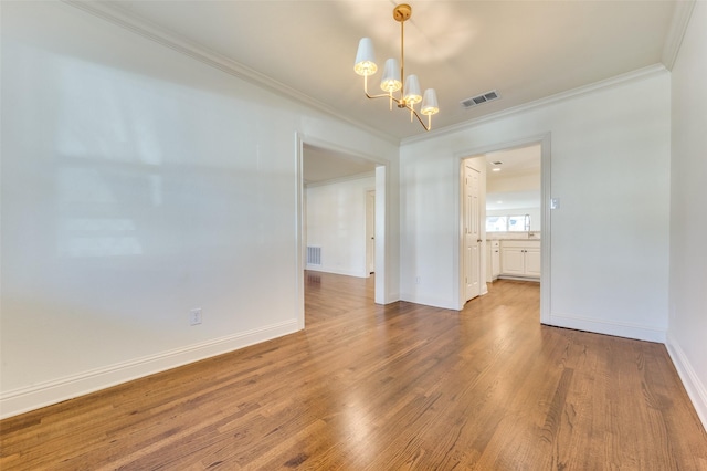 unfurnished room with crown molding, hardwood / wood-style floors, and a notable chandelier