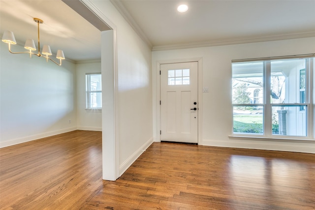 foyer entrance with ornamental molding, wood-type flooring, and a chandelier