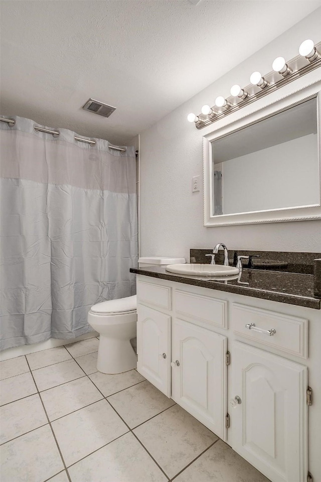 bathroom with visible vents, toilet, a textured ceiling, vanity, and tile patterned floors