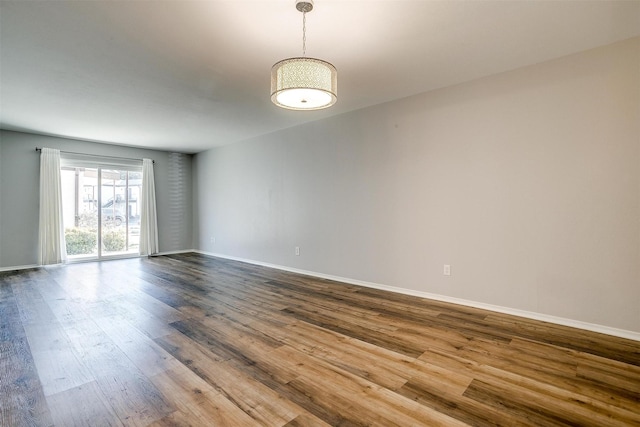 spare room with dark wood finished floors and baseboards