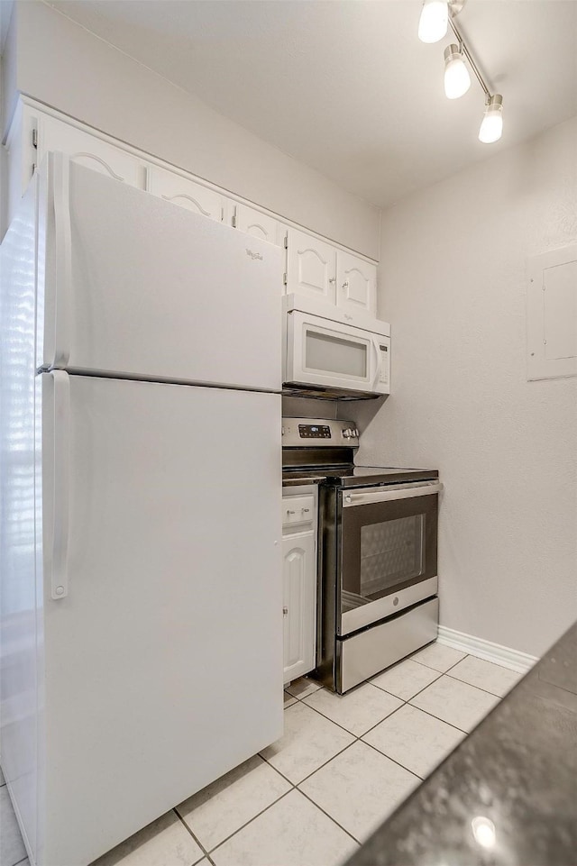 kitchen with white appliances, light tile patterned floors, white cabinets, dark countertops, and rail lighting