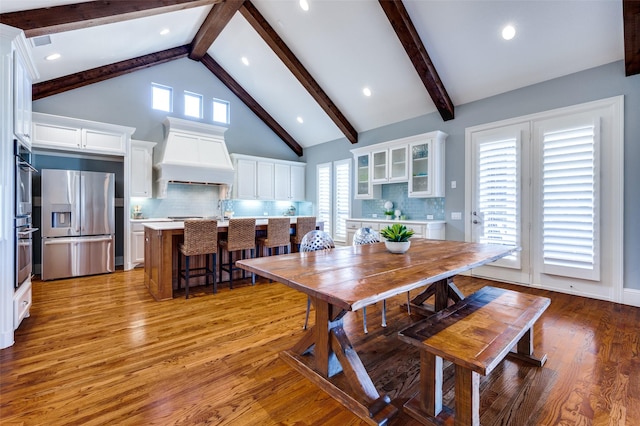 dining area with a wealth of natural light, high vaulted ceiling, beamed ceiling, and light wood-type flooring