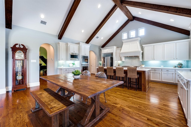 dining area with sink, beam ceiling, high vaulted ceiling, and dark hardwood / wood-style floors