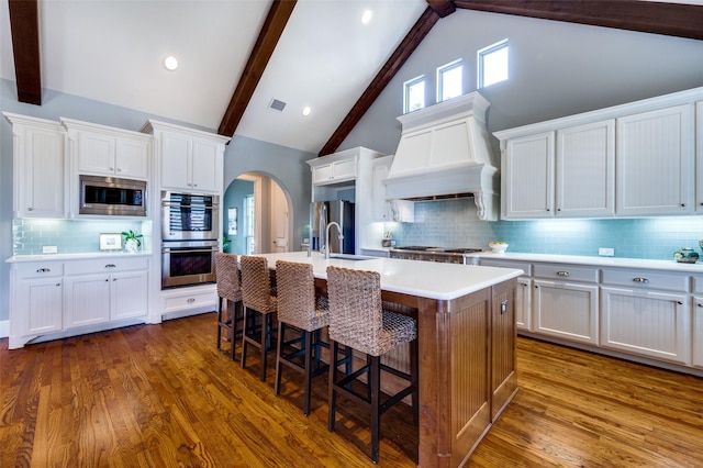 kitchen featuring sink, appliances with stainless steel finishes, white cabinetry, an island with sink, and custom exhaust hood