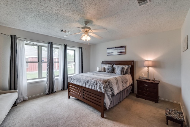 bedroom featuring ceiling fan, light colored carpet, and a textured ceiling