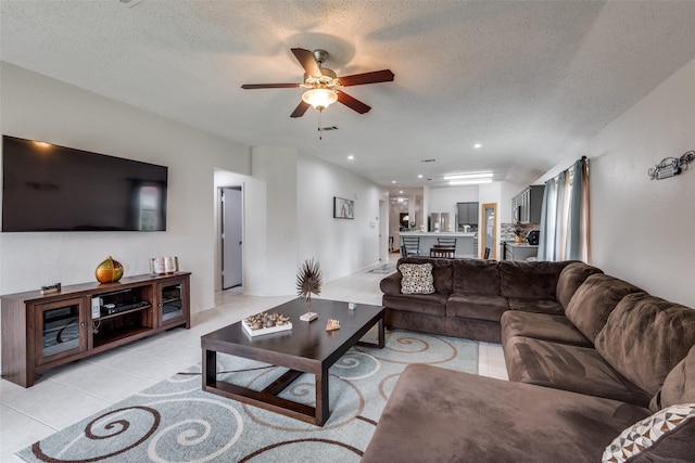 living room with ceiling fan, a textured ceiling, and light tile patterned floors