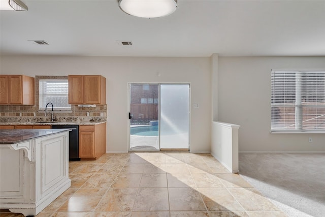 kitchen featuring tasteful backsplash, black dishwasher, sink, and light tile patterned floors