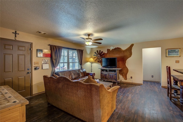 living room with dark wood-type flooring, ceiling fan, and a textured ceiling