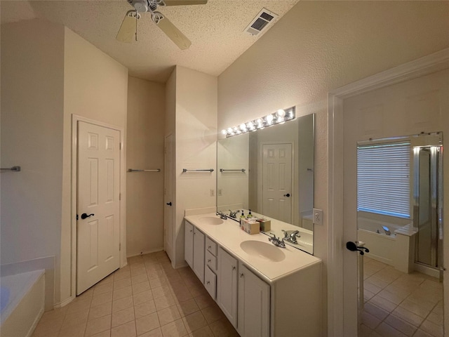 bathroom with a washtub, ceiling fan, tile patterned flooring, vanity, and a textured ceiling