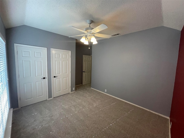 unfurnished bedroom featuring vaulted ceiling, carpet flooring, and a textured ceiling