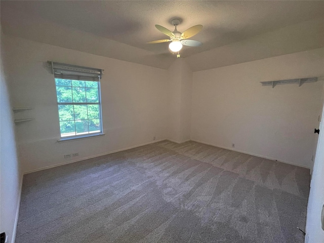 spare room featuring ceiling fan, carpet flooring, and vaulted ceiling