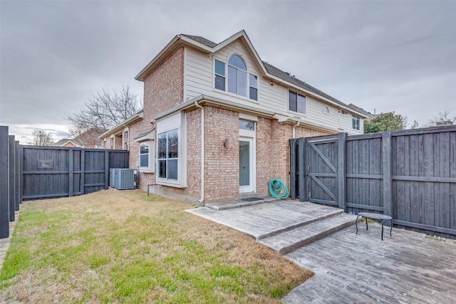 rear view of property featuring central AC unit, a lawn, and a patio area