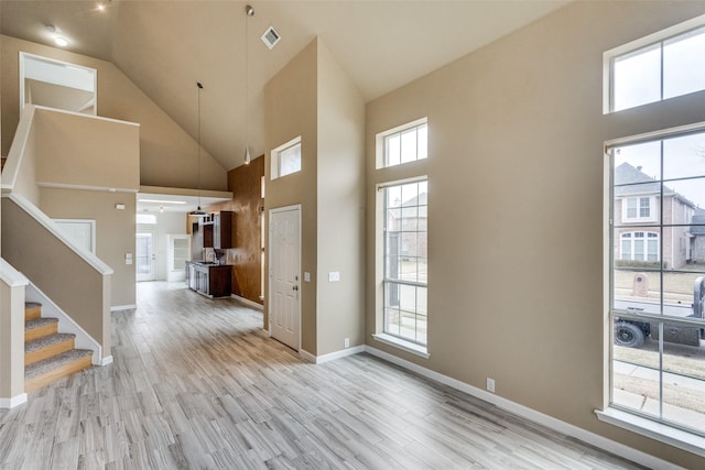 entryway with high vaulted ceiling and light hardwood / wood-style floors