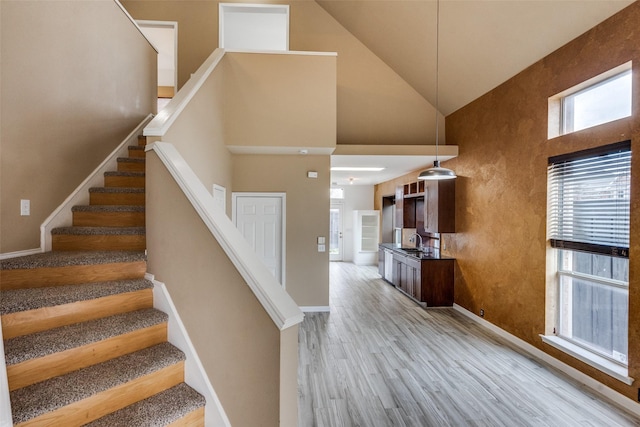 stairway with high vaulted ceiling, wood-type flooring, and sink